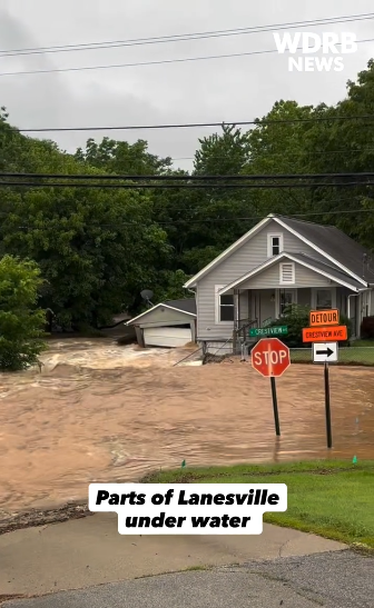 The same home on June 9, 2026, with fast-moving brown floodwater covering the yard and street around a stop sign.